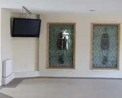 information digital signage TV in the reception area of a church next to stained glass windows